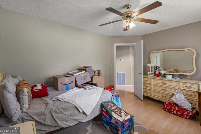 bedroom with wood finished floors, a textured ceiling, and a ceiling fan
