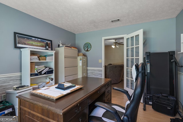 home office featuring light wood finished floors, a ceiling fan, and a textured ceiling