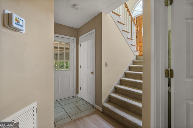 foyer featuring stairs, baseboards, and light wood-style flooring