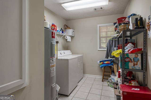 clothes washing area featuring washer and clothes dryer, electric water heater, light tile patterned flooring, a textured ceiling, and baseboards