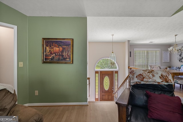 foyer featuring wood finished floors, a chandelier, a textured ceiling, and baseboards
