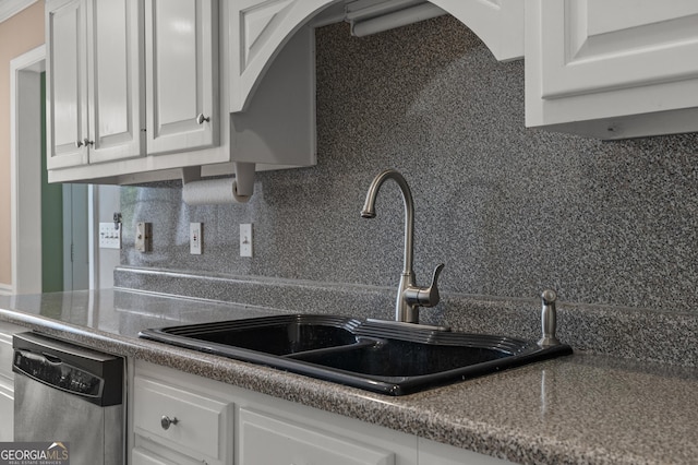 kitchen with a sink, stainless steel dishwasher, tasteful backsplash, white cabinets, and dark countertops