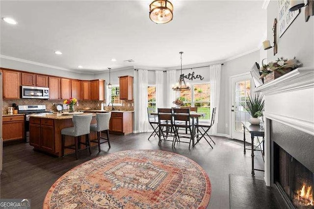 214 Crestmont Way, Canton, GA 30114 - kitchen featuring stainless steel appliances, a warm lit fireplace, ornamental molding, decorative backsplash, and a breakfast bar