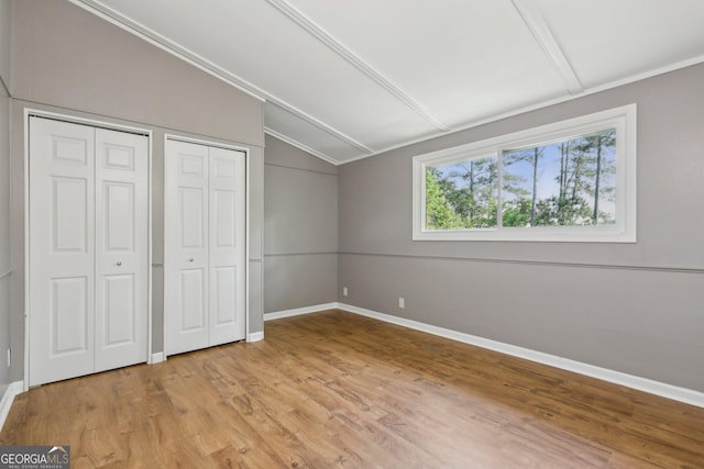 54 Owl Ct, Monticello, GA 31064 - unfurnished bedroom with lofted ceiling, multiple closets, light wood-style floors, baseboards, and ornamental molding