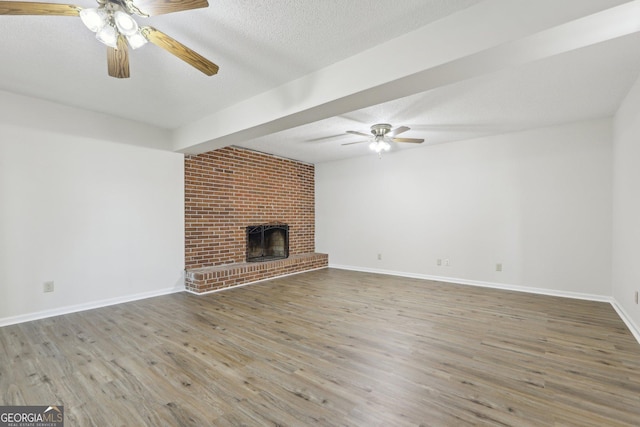54 Owl Ct, Monticello, GA 31064 - unfurnished living room with ceiling fan, wood finished floors, a textured ceiling, a brick fireplace, and baseboards