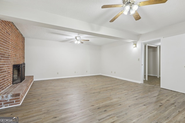 54 Owl Ct, Monticello, GA 31064 - unfurnished living room with a ceiling fan, wood finished floors, a brick fireplace, and a textured ceiling