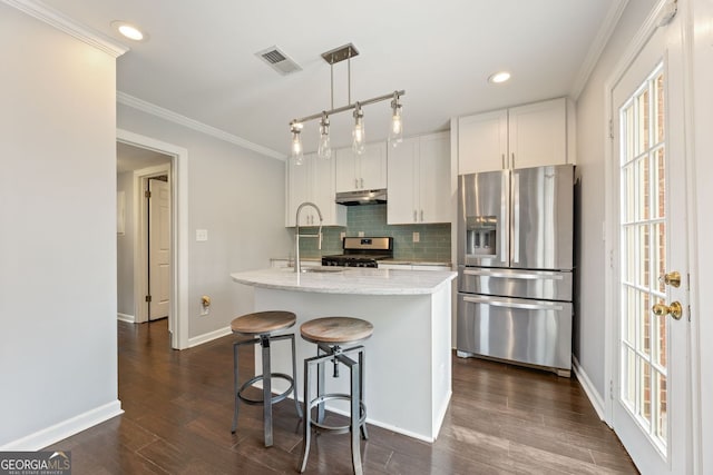 27 Jefferson Hill Pl NE, Atlanta, GA 30342 - kitchen with stainless steel appliances, under cabinet range hood, tasteful backsplash, crown molding, and an island with sink