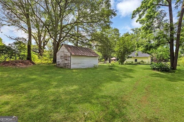 view of green lawn featuring a storage unit and an outbuilding