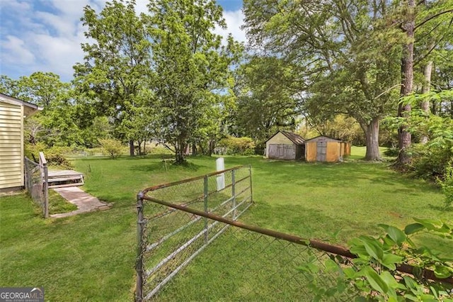 view of yard featuring a storage unit, an outbuilding, and view of wooded area
