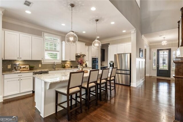 3000 Haven Mill Ln, Milton, GA 30004 - kitchen featuring appliances with stainless steel finishes, ornamental molding, white cabinets, a center island, and tasteful backsplash