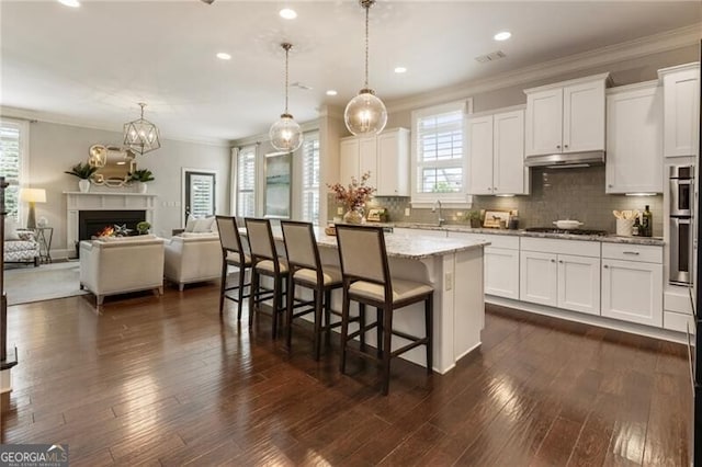 3000 Haven Mill Ln, Milton, GA 30004 - kitchen with stainless steel gas stovetop, a kitchen breakfast bar, light stone counters, white cabinetry, and crown molding