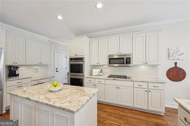 kitchen featuring stainless steel appliances, crown molding, decorative backsplash, white cabinets, and light stone counters