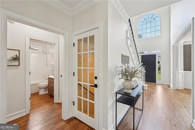entrance foyer with wood finished floors, crown molding, and baseboards