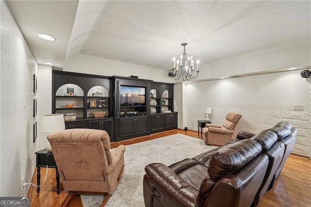 living area featuring wood finished floors, a chandelier, and a textured ceiling