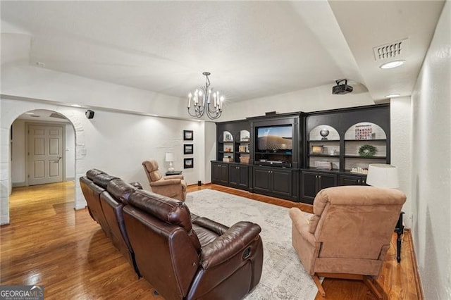 living room with arched walkways, wood finished floors, and a chandelier