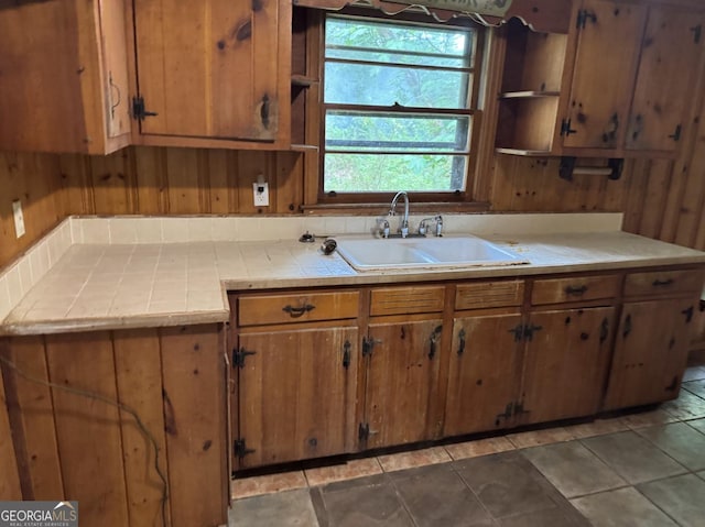 4720 Ben Hill Rd, South Fulton, GA 30349 - kitchen featuring a sink, open shelves, tile countertops, brown cabinetry, and wood walls