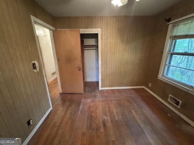 4720 Ben Hill Rd, South Fulton, GA 30349 - unfurnished bedroom featuring wood-type flooring, wood walls, a closet, and baseboards