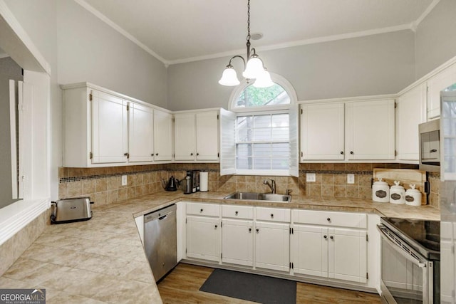 kitchen featuring appliances with stainless steel finishes, a sink, white cabinets, tasteful backsplash, and crown molding