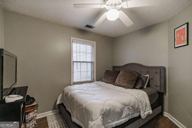 bedroom featuring baseboards, dark wood finished floors, ceiling fan, and a textured ceiling