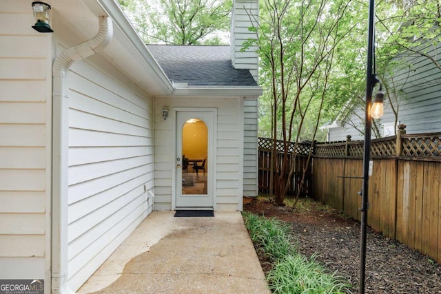 entrance to property with roof with shingles and fence