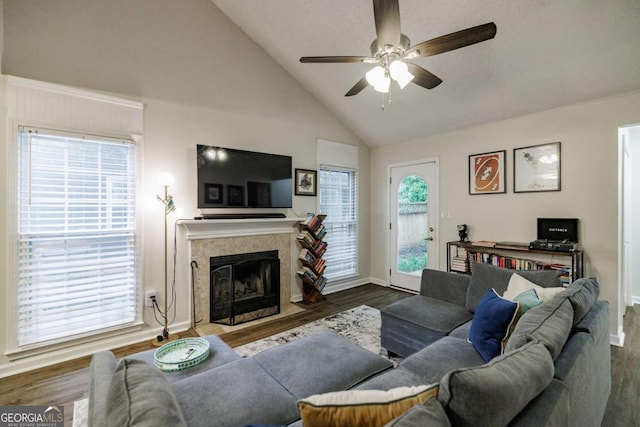 living area featuring a ceiling fan, dark wood-style flooring, a fireplace, baseboards, and high vaulted ceiling