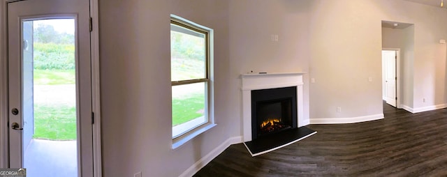395 Brooks Village Dr, Pendergrass, GA 30567 - unfurnished living room featuring dark wood-style floors, baseboards, and a glass covered fireplace