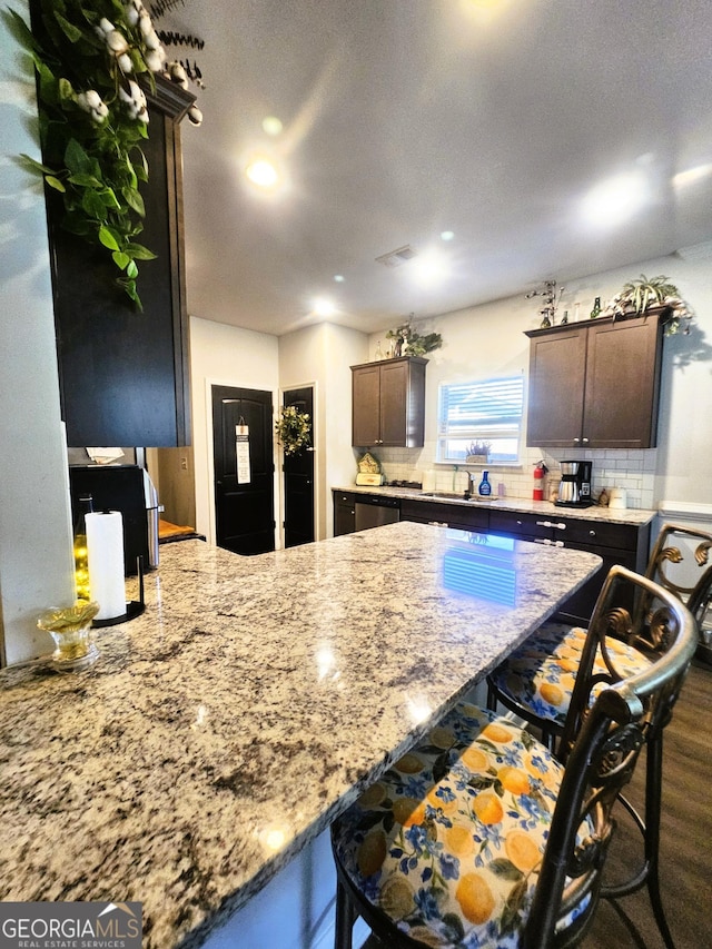 395 Brooks Village Dr, Pendergrass, GA 30567 - kitchen featuring a breakfast bar, dark brown cabinets, light stone counters, and recessed lighting