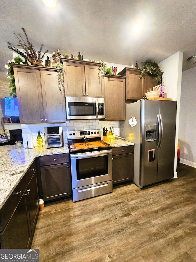 395 Brooks Village Dr, Pendergrass, GA 30567 - kitchen with appliances with stainless steel finishes, wood finished floors, tasteful backsplash, light stone counters, and dark brown cabinets