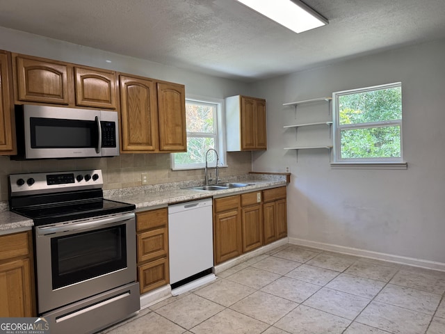 13327 US Highway 17, Woodbine, GA 31569 - kitchen with appliances with stainless steel finishes, brown cabinets, light countertops, a textured ceiling, and tasteful backsplash