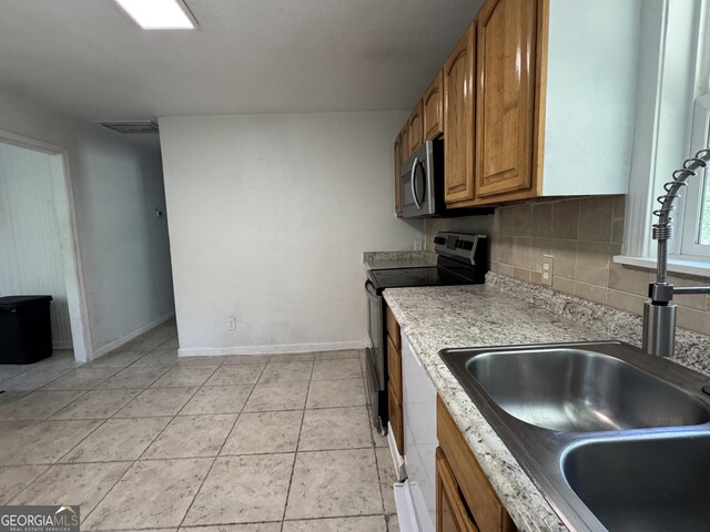 13327 US Highway 17, Woodbine, GA 31569 - kitchen featuring stainless steel microwave, brown cabinetry, decorative backsplash, range with electric stovetop, and light tile patterned floors