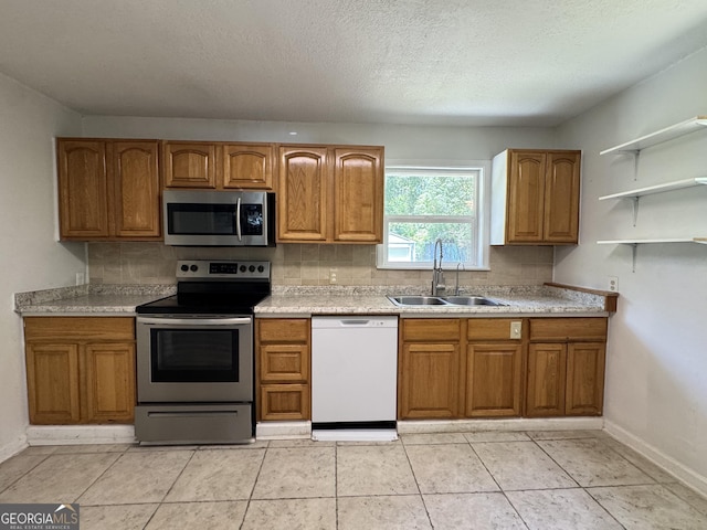 13327 US Highway 17, Woodbine, GA 31569 - kitchen with appliances with stainless steel finishes, decorative backsplash, brown cabinets, light countertops, and a textured ceiling