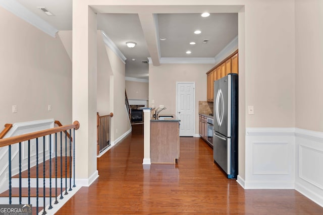 kitchen featuring freestanding refrigerator, ornamental molding, dark wood-type flooring, recessed lighting, and a center island with sink