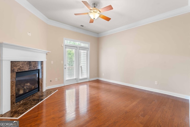 unfurnished living room with wood finished floors, a fireplace, a ceiling fan, ornamental molding, and baseboards