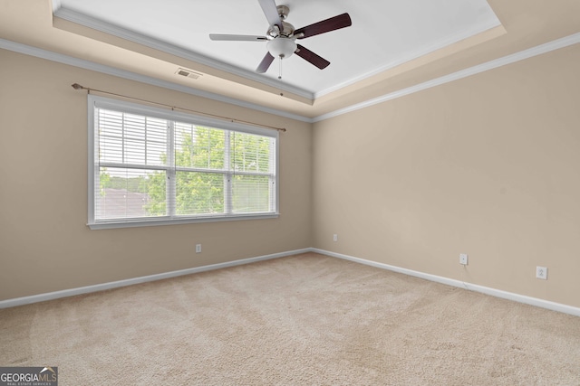 carpeted spare room featuring a tray ceiling, ornamental molding, baseboards, and ceiling fan