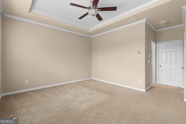 carpeted empty room with ceiling fan, a tray ceiling, crown molding, and baseboards