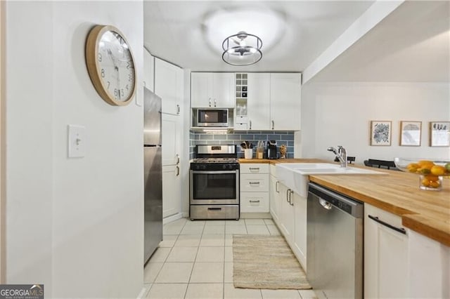 620 Peachtree St NE Unit 403, Atlanta, GA 30308 - kitchen with appliances with stainless steel finishes, butcher block counters, light tile patterned floors, decorative backsplash, and white cabinets