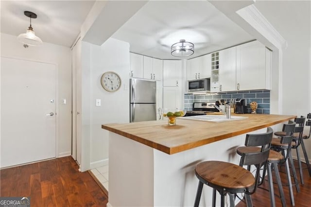 620 Peachtree St NE Unit 403, Atlanta, GA 30308 - kitchen featuring stainless steel appliances, wood counters, a peninsula, and white cabinetry