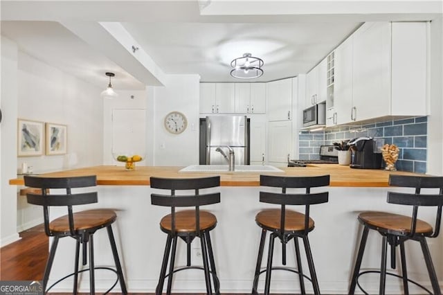 620 Peachtree St NE Unit 403, Atlanta, GA 30308 - kitchen with appliances with stainless steel finishes, wood counters, a peninsula, decorative backsplash, and a sink