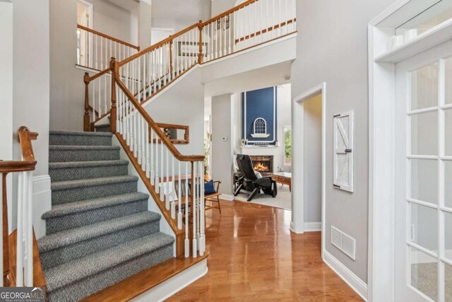 1316 Wind Chime Ct, Lawrenceville, GA 30045 - stairway with a towering ceiling, wood finished floors, a lit fireplace, and baseboards