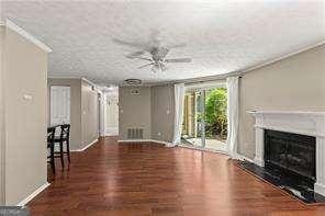 1371 Keys Lake Dr NE, Atlanta, GA 30319 - unfurnished living room featuring a fireplace, wood finished floors, ceiling fan, baseboards, and ornamental molding