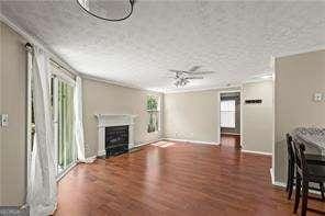 1371 Keys Lake Dr NE, Atlanta, GA 30319 - unfurnished living room featuring a fireplace, wood finished floors, baseboards, ceiling fan, and ornamental molding