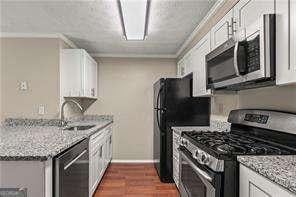 1371 Keys Lake Dr NE, Atlanta, GA 30319 - kitchen featuring stainless steel appliances, white cabinetry, dark wood-style flooring, light stone countertops, and a sink