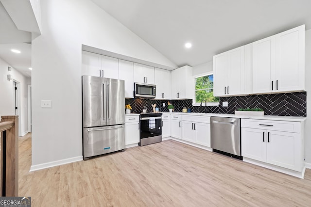 4058 Daron Ct, Ellenwood, GA 30294 - kitchen featuring appliances with stainless steel finishes, vaulted ceiling, light wood finished floors, white cabinets, and a sink