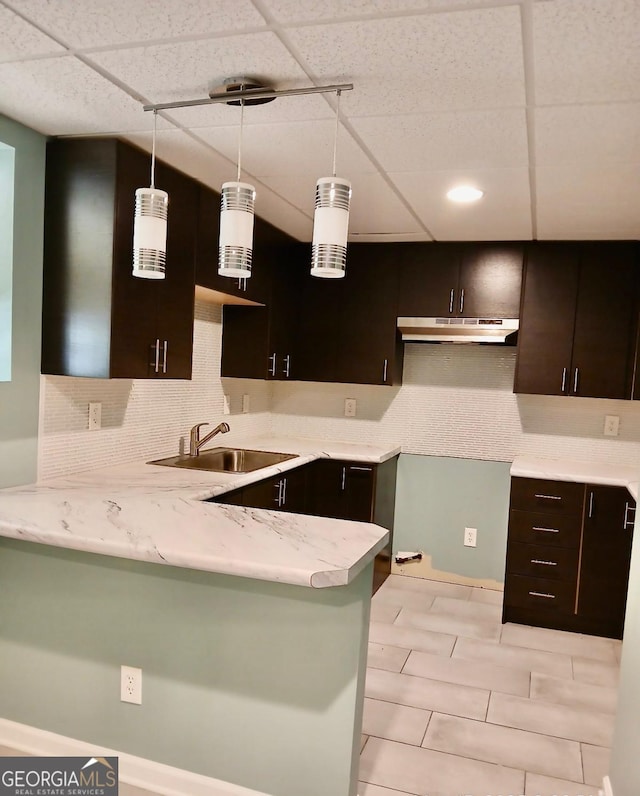 1202 Laurel Cliff Dr SE, Smyrna, GA 30082 - kitchen featuring a sink, under cabinet range hood, a peninsula, backsplash, and dark brown cabinetry