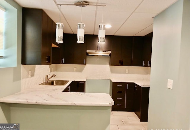1202 Laurel Cliff Dr SE, Smyrna, GA 30082 - kitchen with a sink, under cabinet range hood, decorative backsplash, a peninsula, and dark brown cabinetry