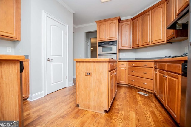 5995 Azalea Ridge Dr, Douglasville, GA 30135 - kitchen with under cabinet range hood, light wood-style floors, ornamental molding, a kitchen island, and double oven