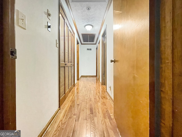 hallway with light wood finished floors and a textured ceiling