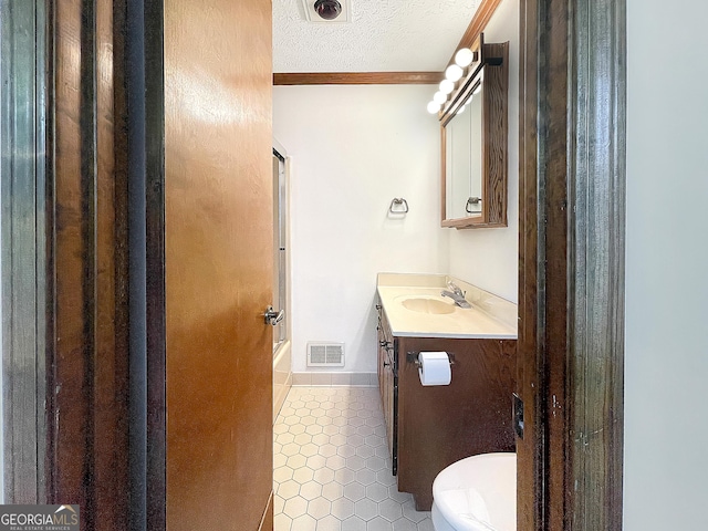 full bath featuring tile patterned flooring, vanity, crown molding, a textured ceiling, and toilet