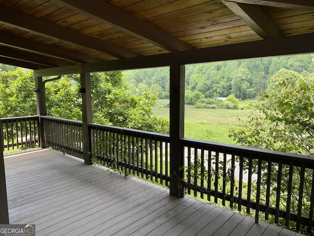 deck featuring a wooded view and a lawn