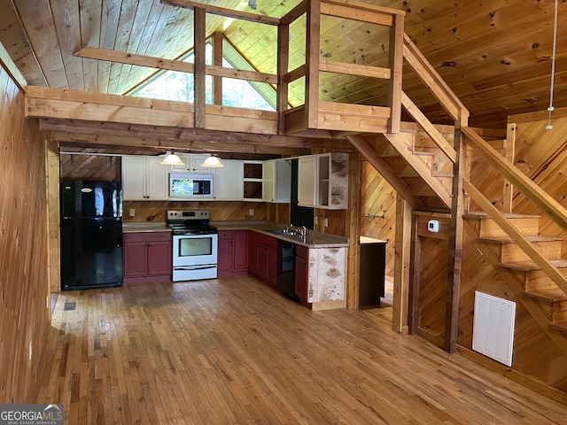 kitchen featuring black appliances, open shelves, wood walls, a sink, and light wood-type flooring